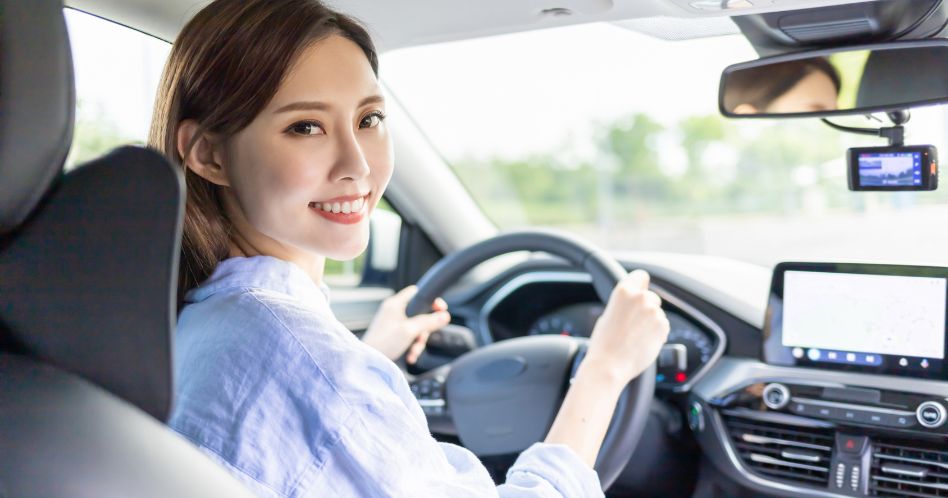 asian women smiling while driving a vehicle