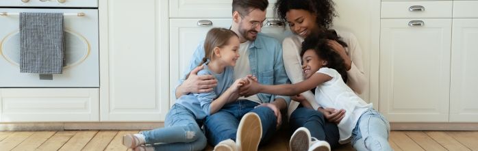 smiling multiracial family sitting on kitchen floor