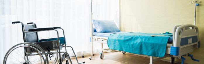 wheelchair and patient bed in hospital room
